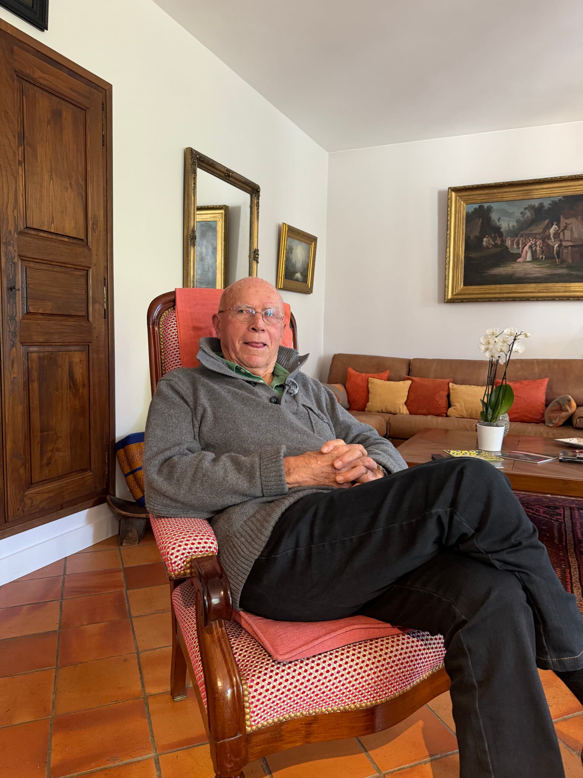 Un homme âgé assis dans un fauteuil, souriant dans son salon