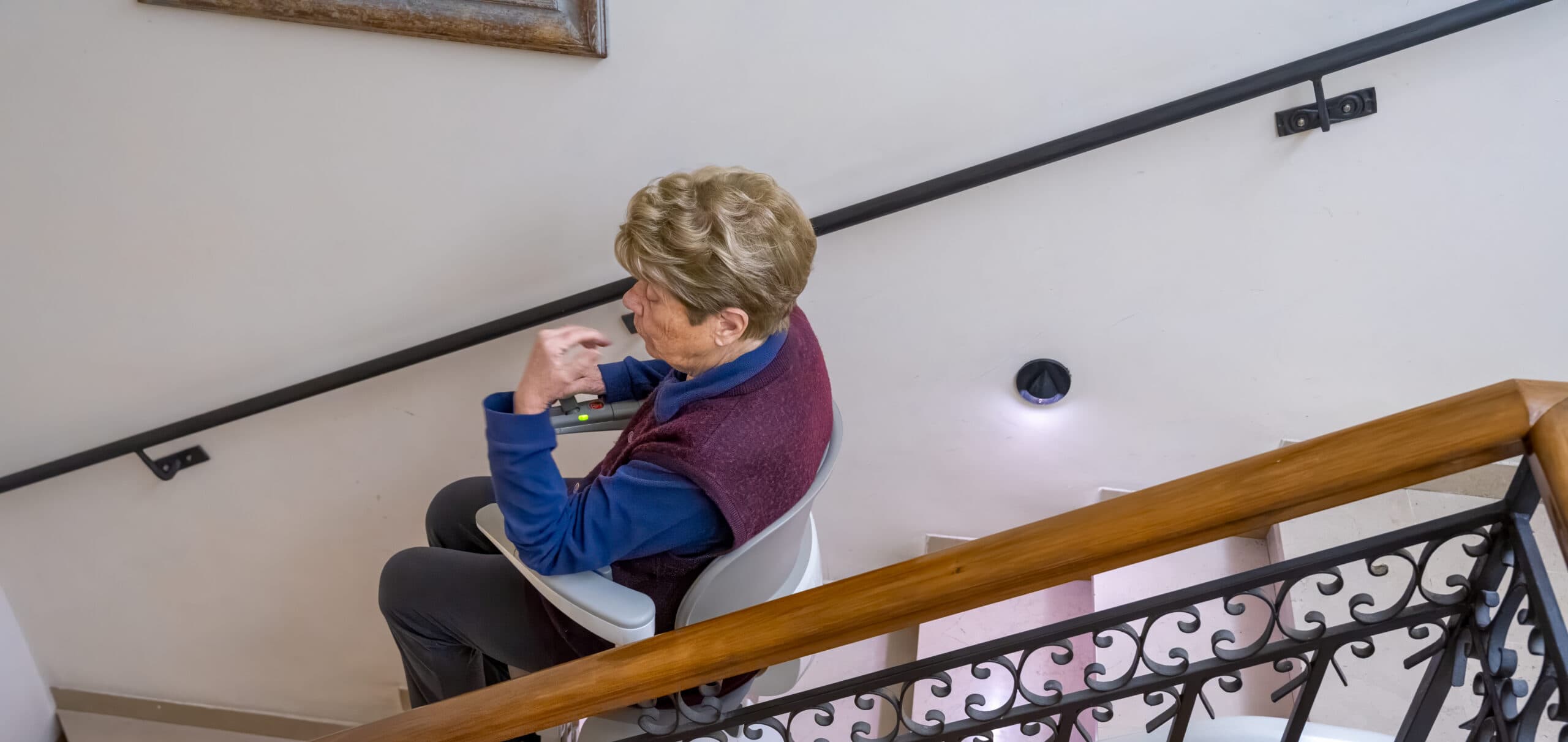 Une femme utilisant un monte-escalier sur rail courbe dans une cage d'escalier